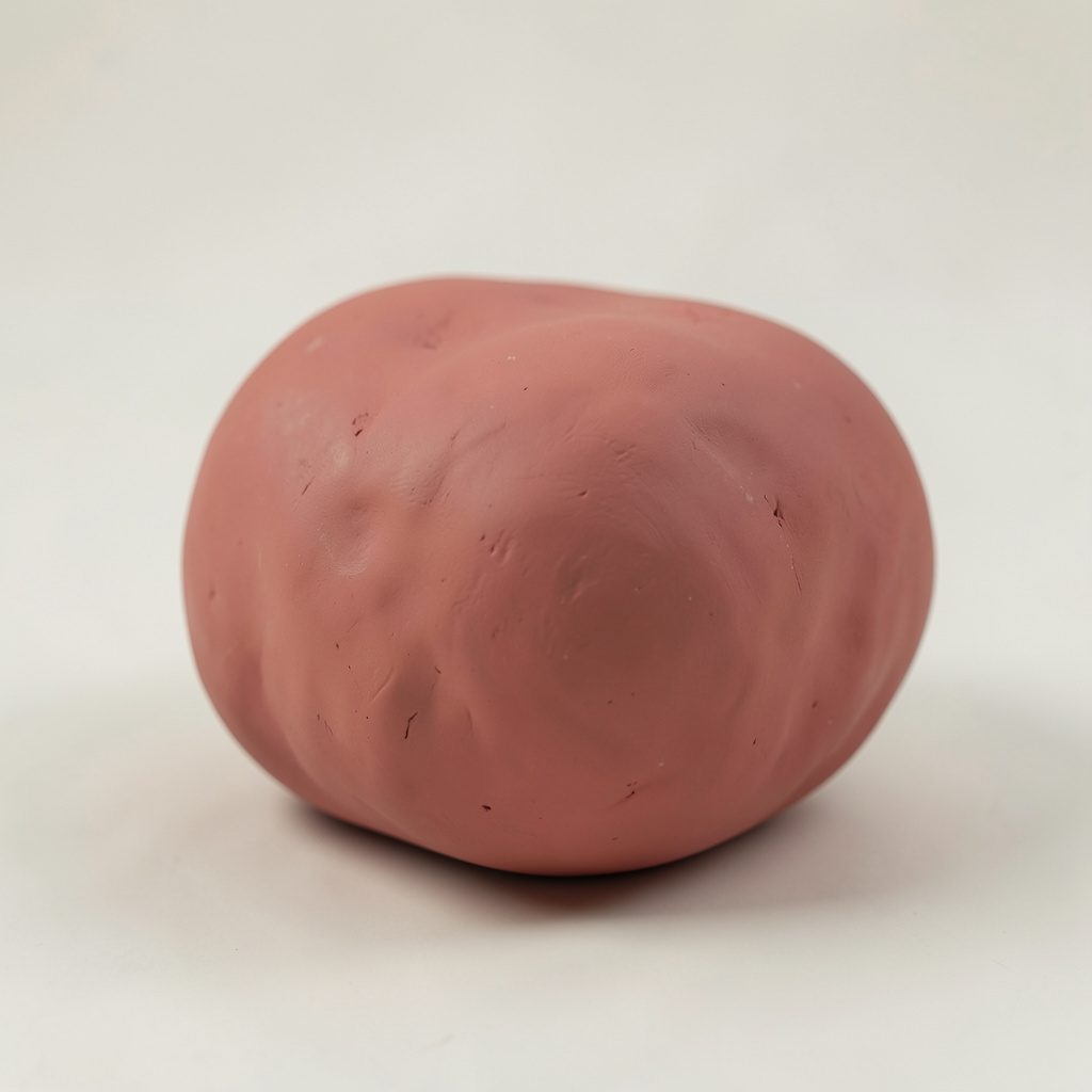 Soft clay-model render of a rounded Android robot figure in muted green tones, set against a warm pastel pink background with gentle handmade textures.